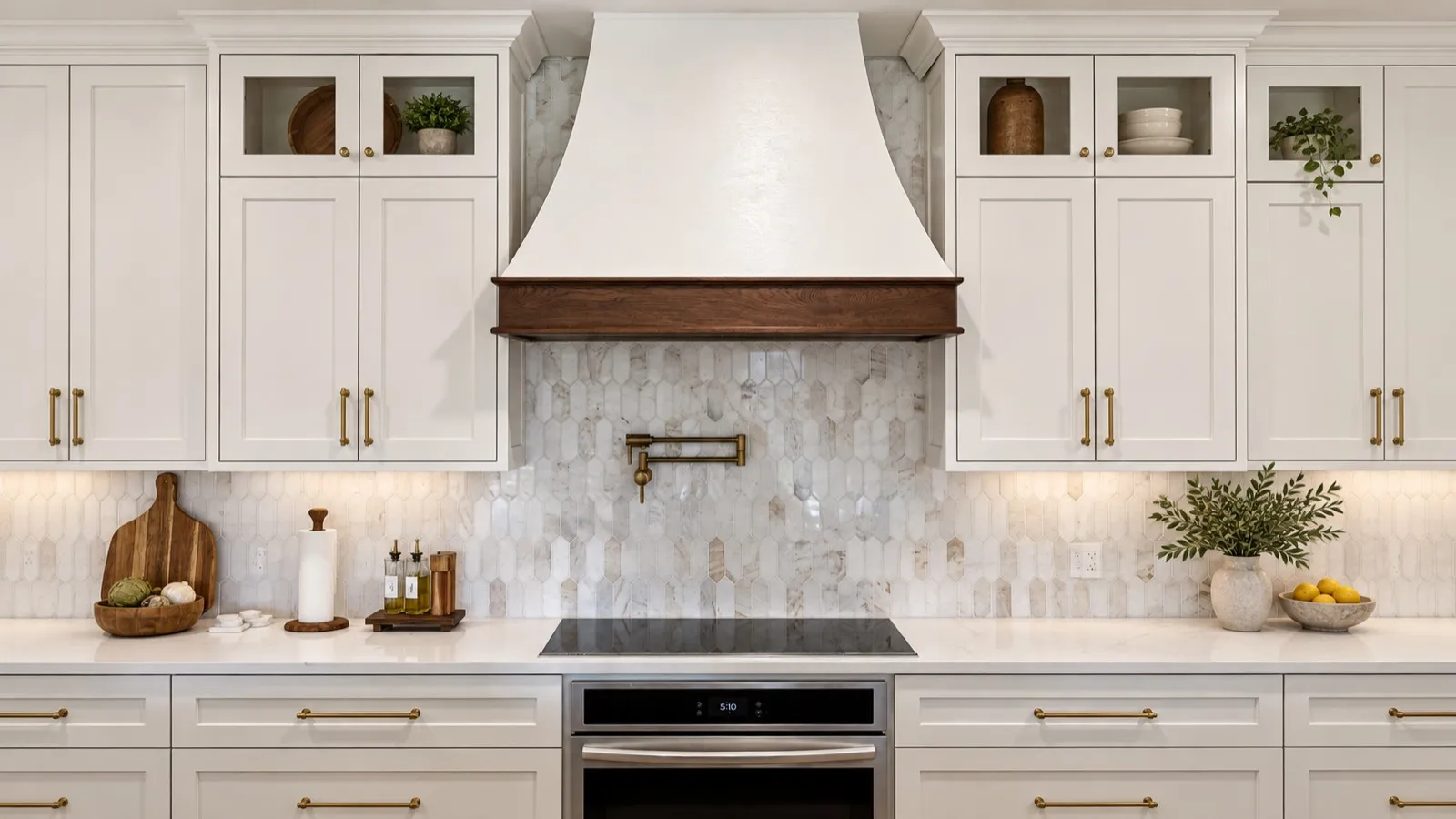 A kitchen range wall with a plaster hood, walnut band, marble picket backsplash and brass hardware
