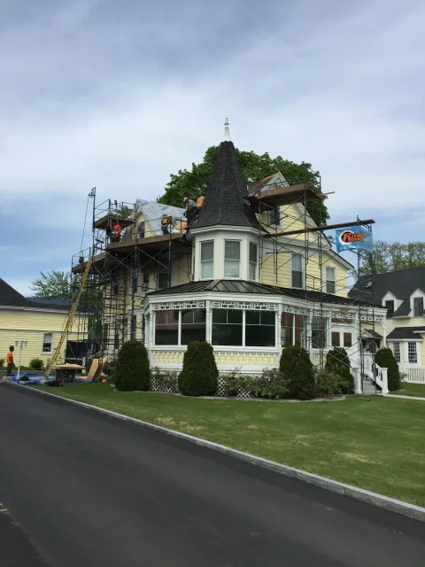 A large house is being remodeled with scaffolding on the roof.