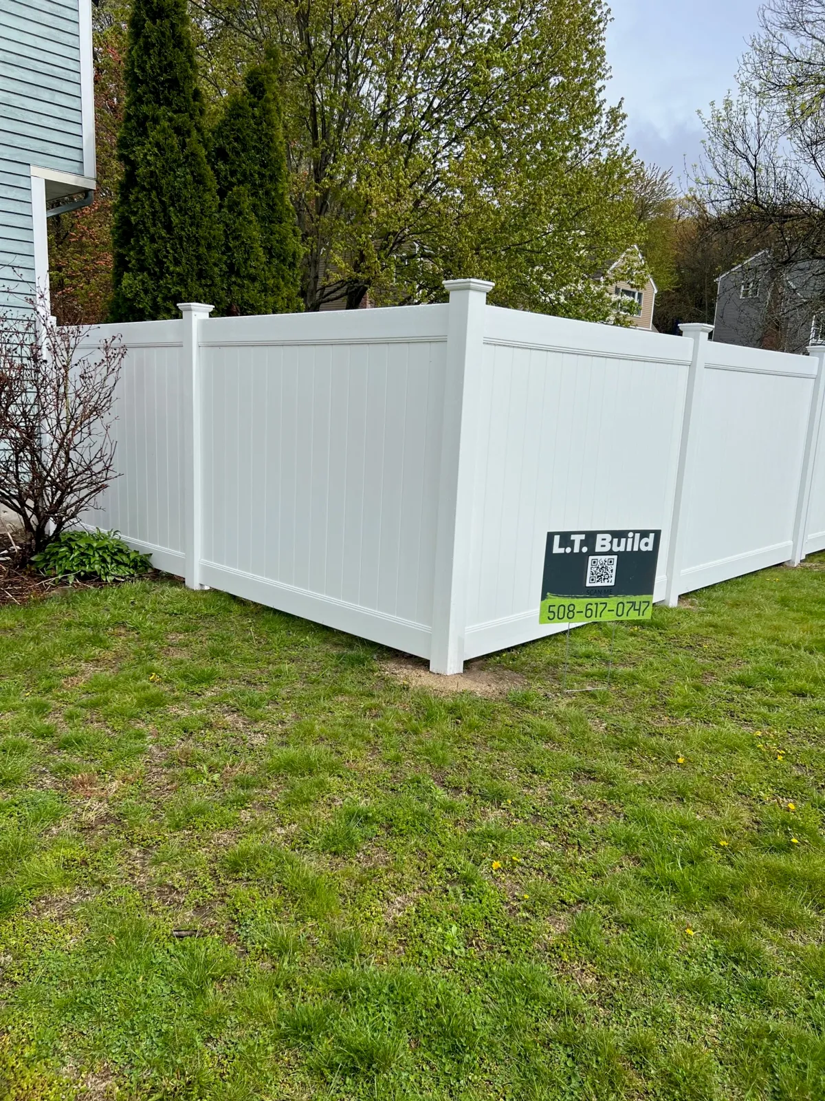 A wooden fence alongside a white fence, creating a contrasting boundary in a serene outdoor setting.