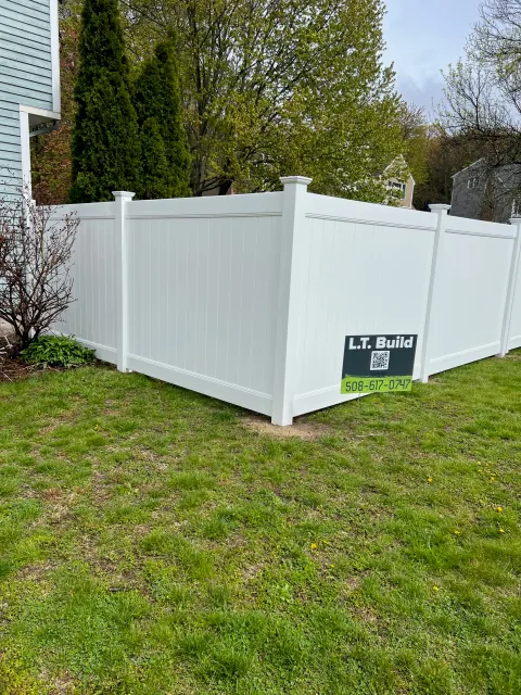 A wooden fence alongside a white fence, creating a contrasting boundary in a serene outdoor setting.