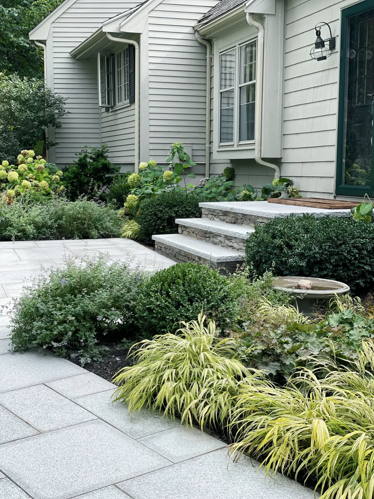 A front yard garden that includes new stone steps and landings, a granite pathway and beautiful garden design that offers superior curb appeal at this Andover landscape.