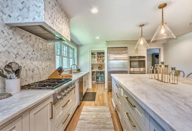 Bright kitchen renovation in Melrose, MA by PEGASUS Design-to-Build showcasing quartz countertops and brass fixtures.-optimized