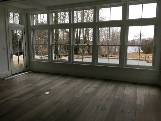 Open interior with bookshelf, ceiling beams, pocket dining doors, and poolside views painted by IAP Inc. for Wellen Construction in Woods Hole, Falmouth MA.