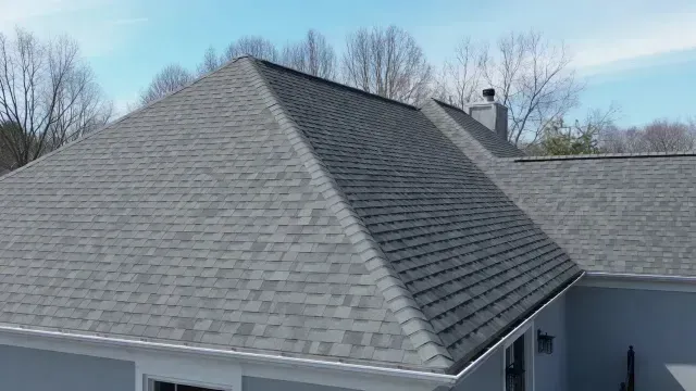 Gray shingled roof on a house with trees in the background