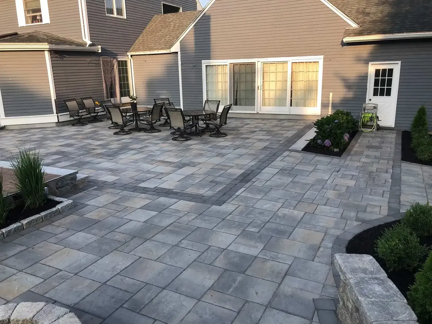 Paver patio with outdoor dining furniture beside a home