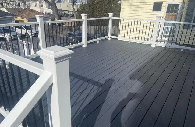 A deck with a white railing and a shadow of a person on it.
