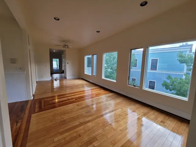Spacious and newly painted living room with large windows and polished hardwood floors on Franklin St, Cambridge, Massachusetts.