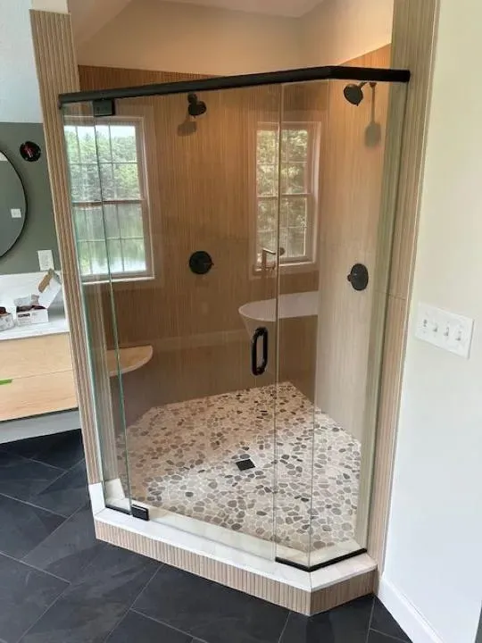 Dreamstate Renovations, LLC - Custom tile shower with glass doors, sleek black flooring, and modern design, showcasing expert bathroom renovation craftsmanship.