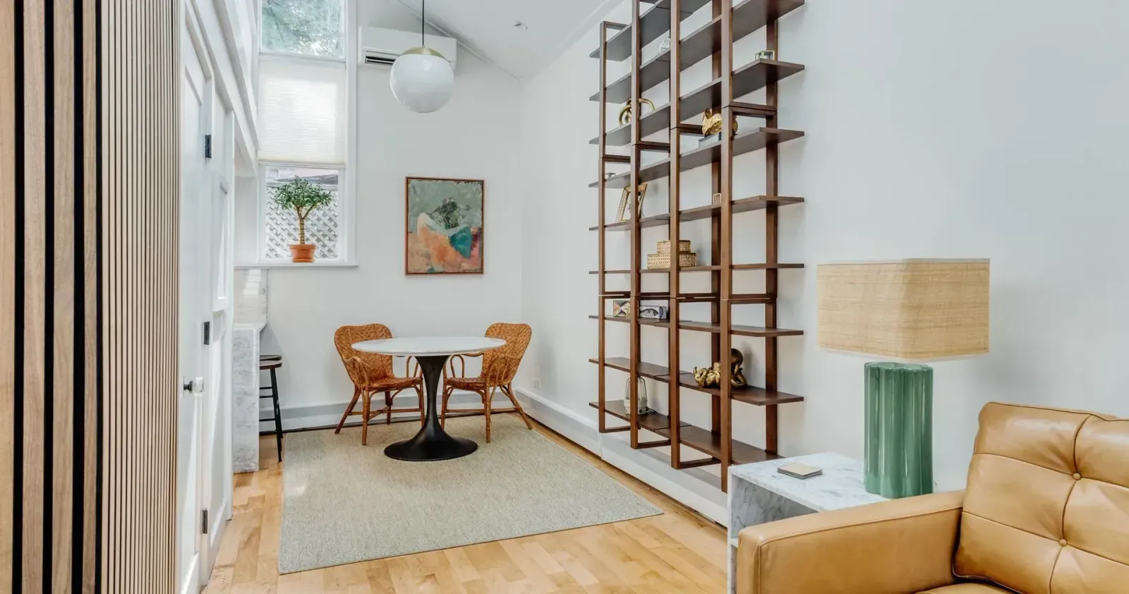 Bright hallway with wooden ladder shelves, small dining table, and tan chair in a modern interior.
