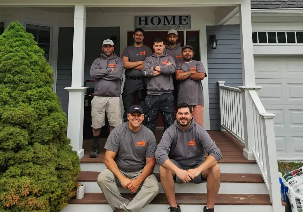 The Imagine Construction field team smiling while posing on the front porch steps of a renovated home.