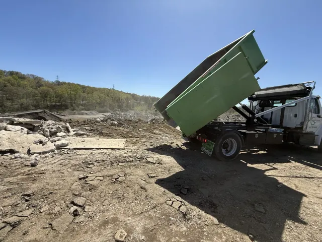 Greenway Dumpster Solutions truck delivering a roll-off dumpster