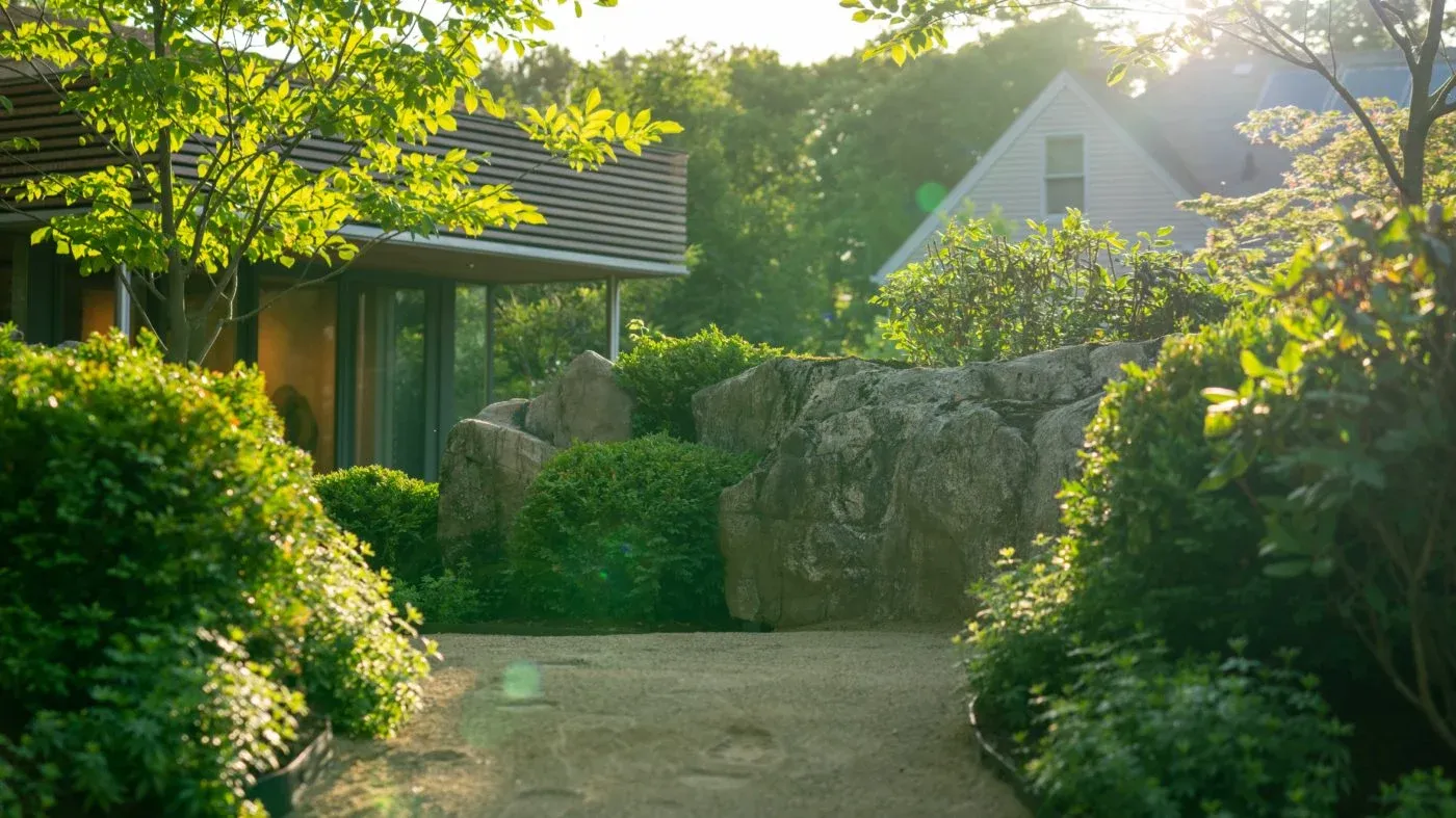 Modern Zen garden with natural stone walls, lush plantings, and a contemporary studio in Massachusetts designed by Land Design Associates.
