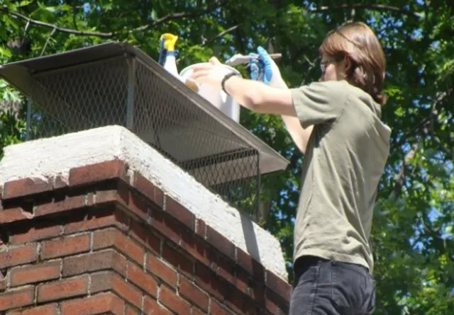 A technician applying waterproofing sealant to a brick chimney crown, provided by Northeast Chimney Sweeps.