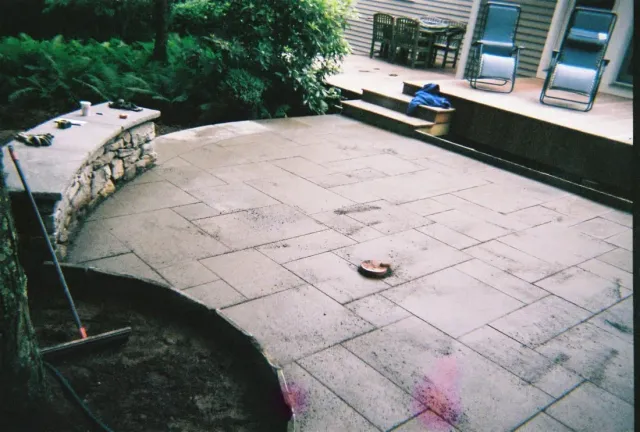 Large bluestone patio with a curved stone seat wall