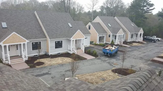 A row of houses with a blue dumpster parked in front of them.