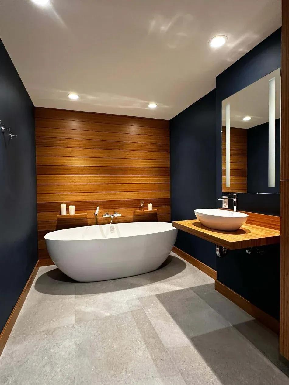 Modern bathroom with a freestanding bathtub, wooden wall, and a floating wooden sink with a vessel sink and mirror.