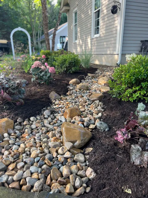 A garden with rocks and flowers in front of a house.