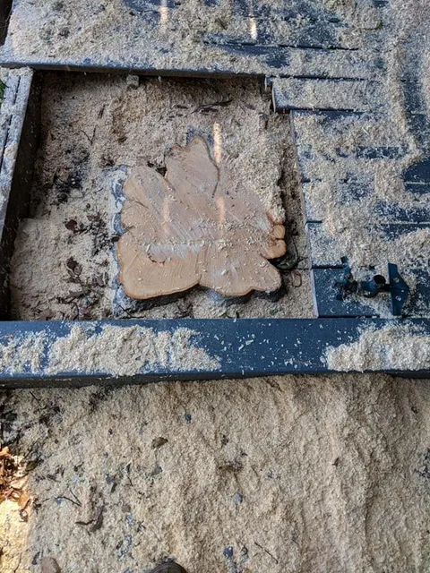 Broken clay tile in a muddy trench with dark framing bars and sand around it