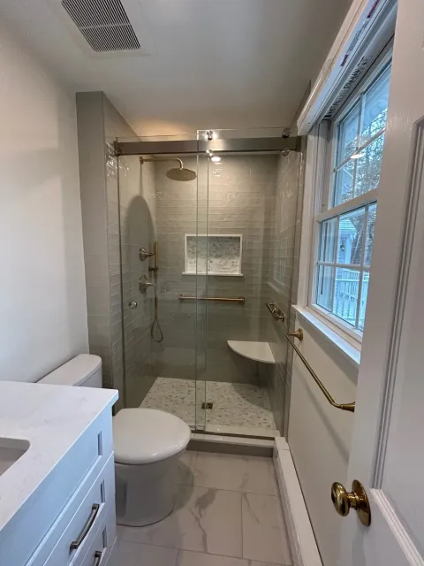 Glass walk-in shower with brushed gold fixtures