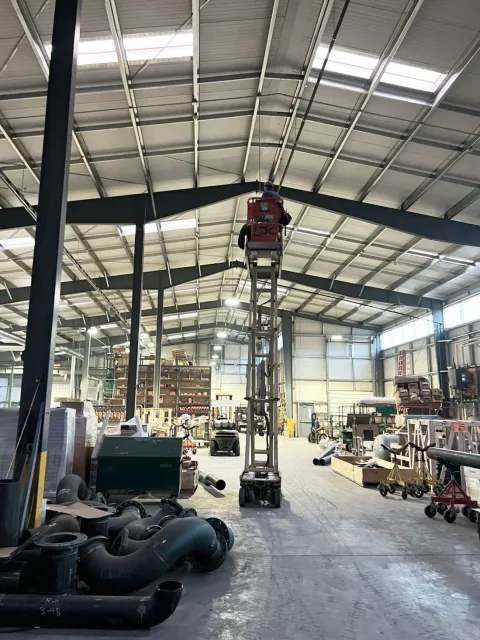 A cherry picker in a giant warehouse with our team members hanging lights in it