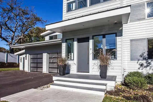 The front of a white house with a black garage door.