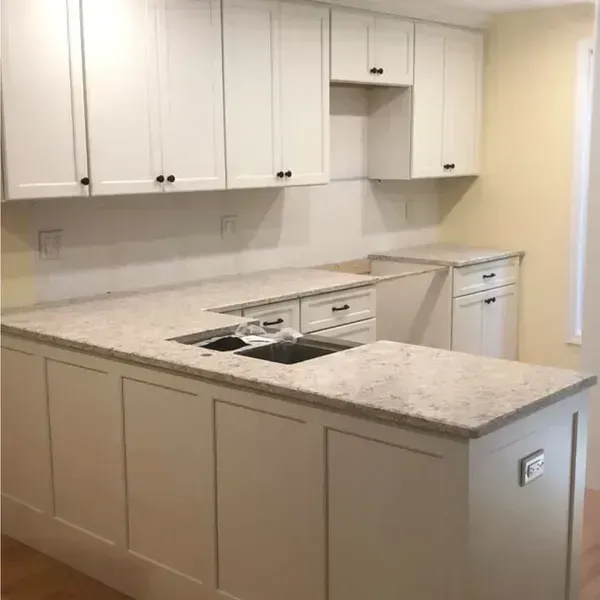 White kitchen with cabinets and countertops. Dark cabinet hardware.