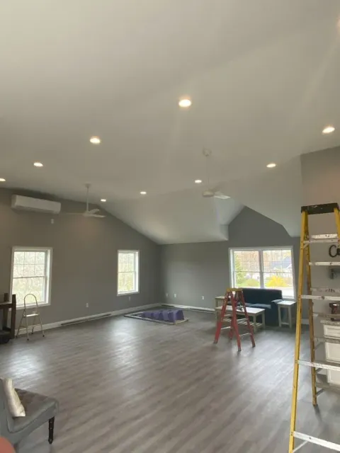Partially finished room with gray floors, recessed lights, windows, ladder, and construction tools