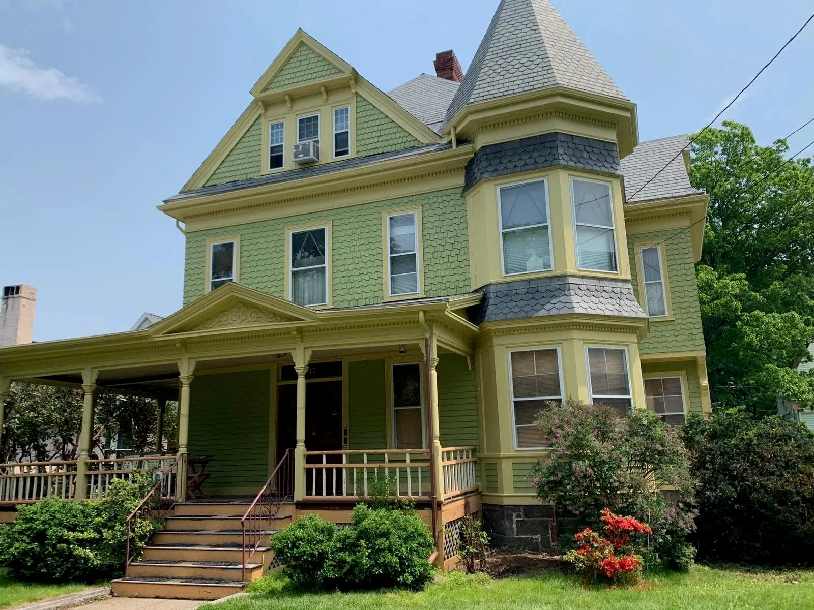 Restored Victorian-style house with yellow and green paint, turret, and porch—exterior project completed by Star Painting Service Group.