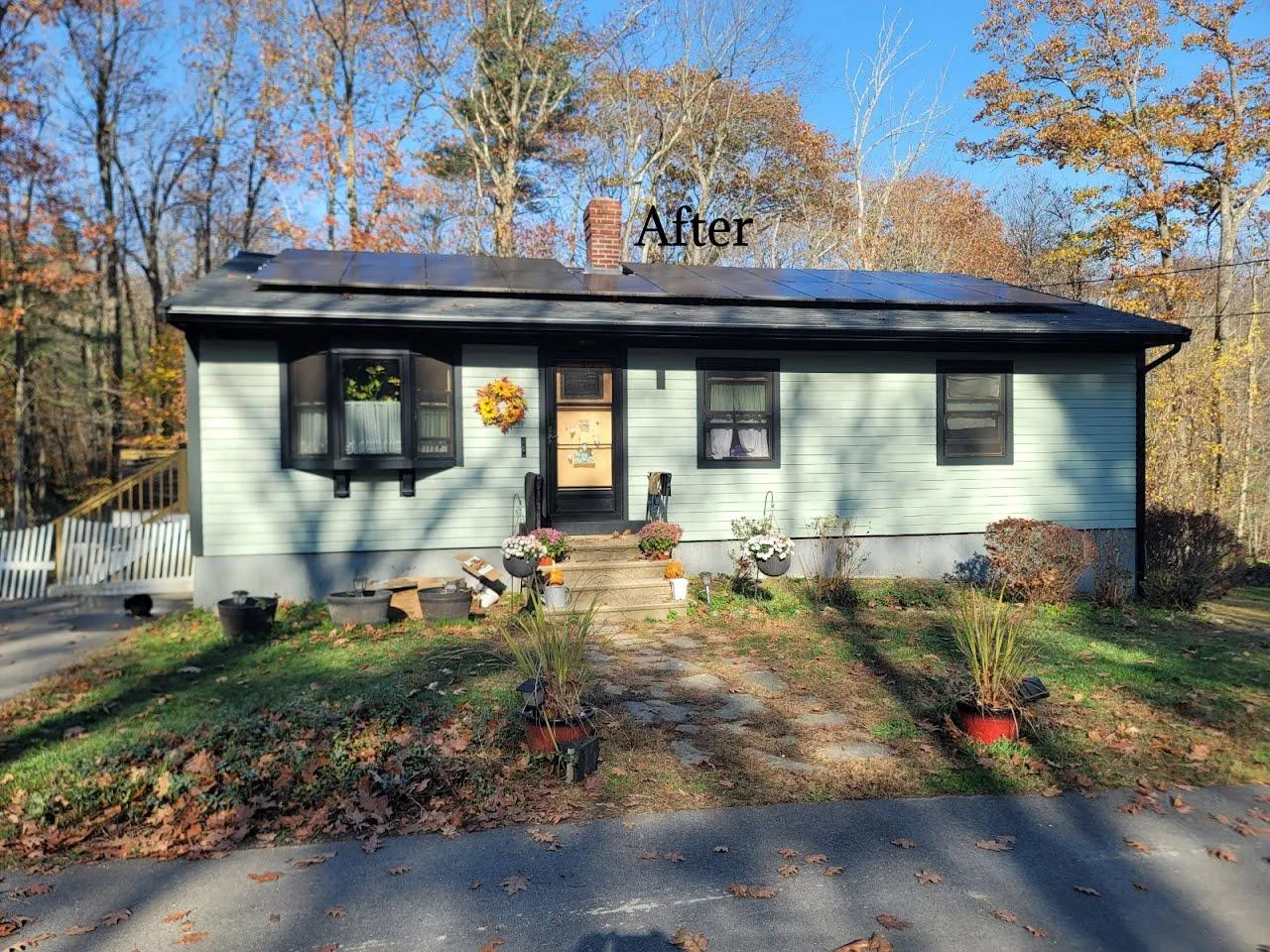 A beautifully restored ranch house featuring a light green exterior, dark green trim, and a vibrant yellow door that pops, painted by Impeccable Painting.