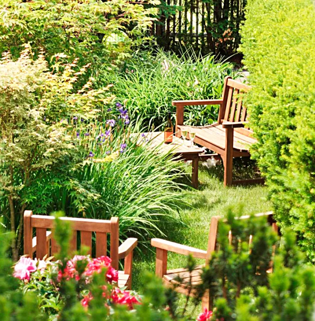 Lush garden with vibrant seasonal plantings and custom wooden benches, designed and installed by Artisan Grounds on the New Hampshire Seacoast.