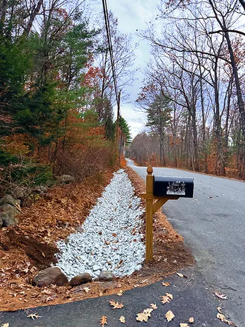 New gravel drainage ditch alongside a rural road and mailbox