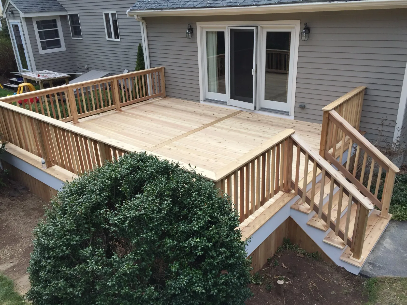 Newly built wooden deck with railing and stairs attached to the back of a house.