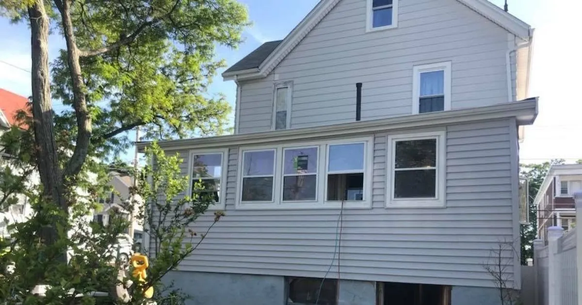 Wide view of enclosed porch renovation with windows and siding