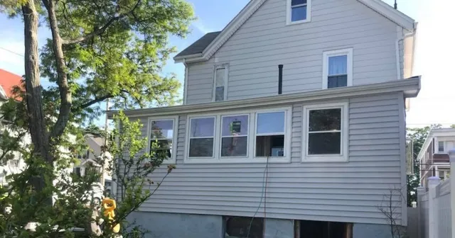 Wide view of enclosed porch renovation with windows and siding