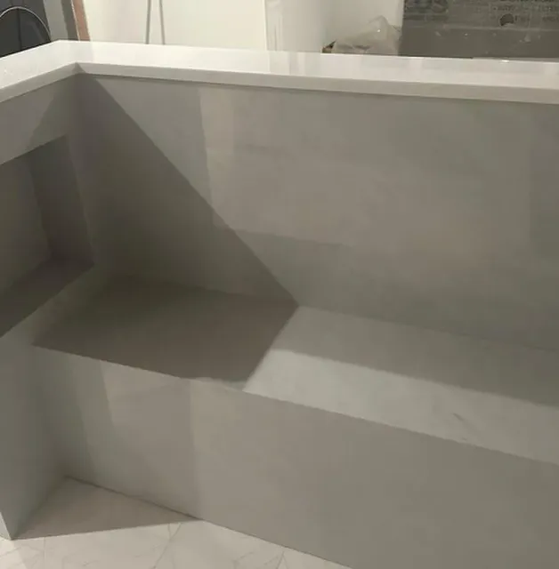 A white bench with a white counter top is sitting in a room.