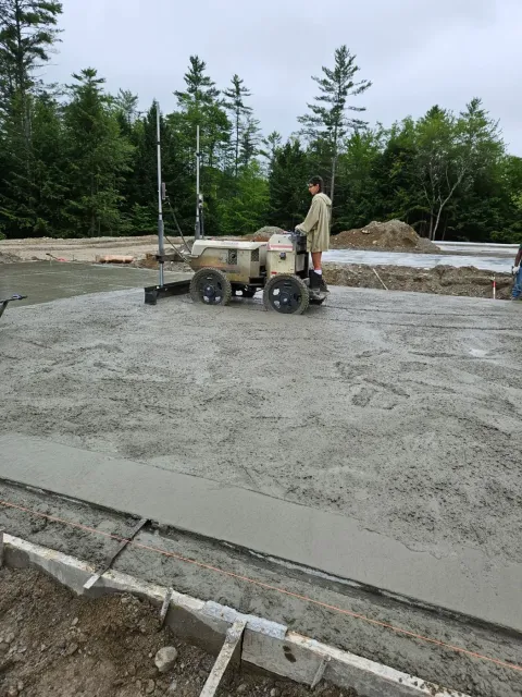 Crew member operating a ride-on power trowel