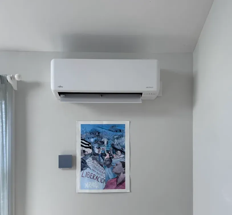 A room with a picture on the wall and a wall mounted air conditioner.