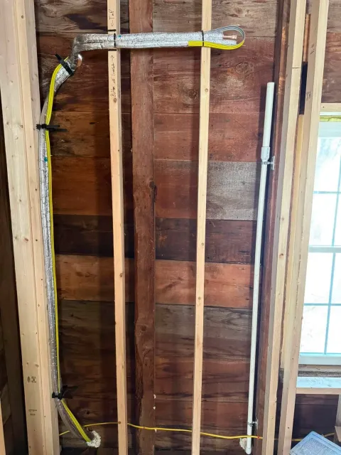 Exposed wall framing with electrical wiring and a window in a partially finished room