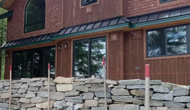 Dry laid fieldstone wall along a cedar lake house in New Hampshire