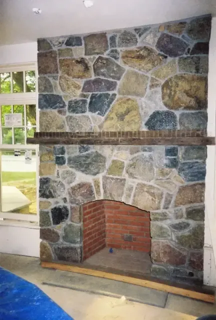 Floor to ceiling interior fieldstone fireplace with a brick firebox