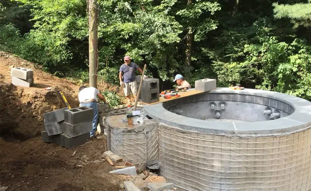 A group of men are working on a large brick structure.