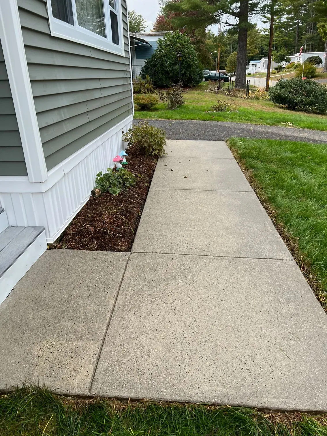 A sidewalk leading to a house with a concrete walkway.