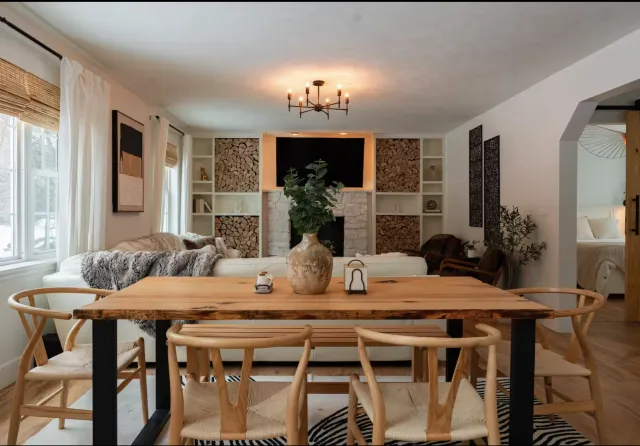 Open living and dining room with a wood table, stone fireplace wall and light wood floors