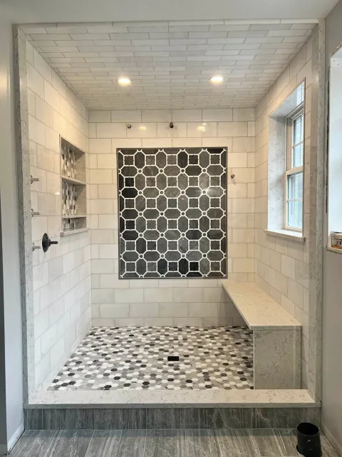 A bathroom with a walk in shower and a bench.