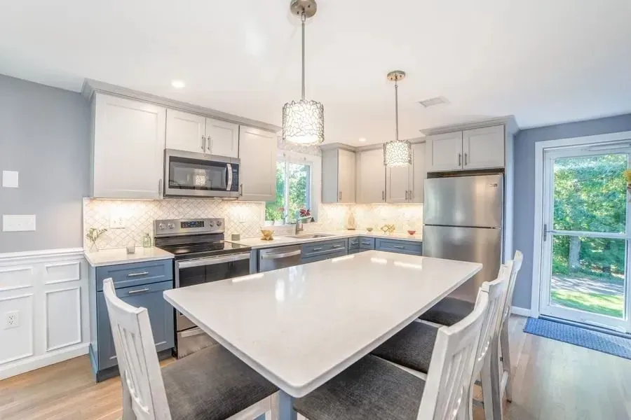 Bright modern kitchen with white cabinets, stainless appliances, and a large island near sliding glass doors