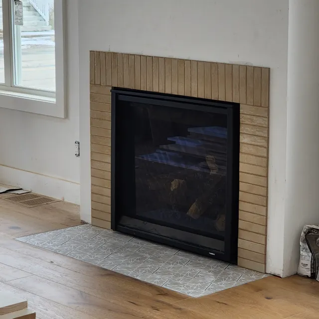 Room view of a fireplace with vertically stacked tile surround and tiled hearth