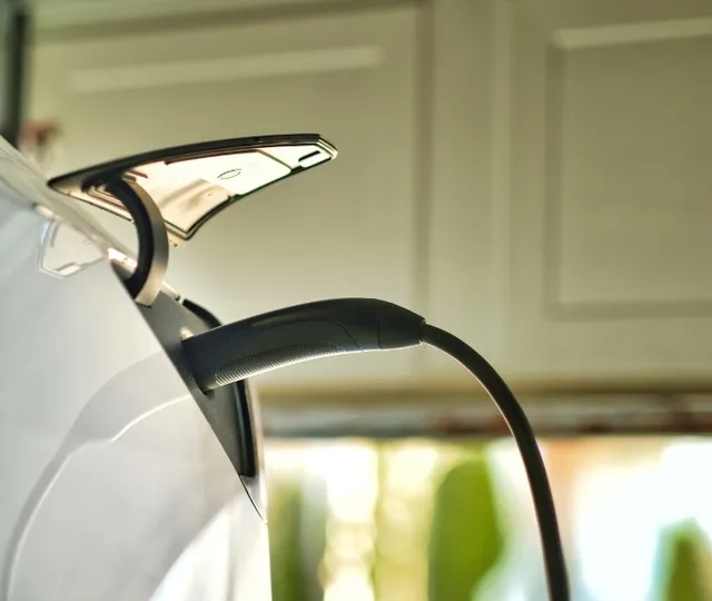 White electric vehicle charging port with sleek curved handle and chrome accents