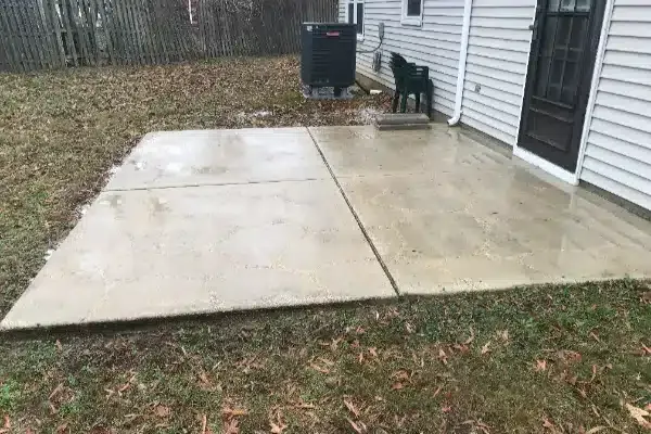 After: A rain-soaked concrete patio next to a house, with a chair and an outdoor air conditioning unit in view.