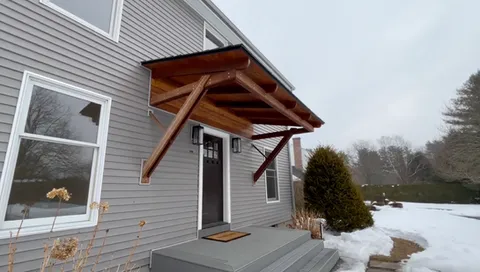 Cantilever awning in African Redwood with angled slate-style roof
