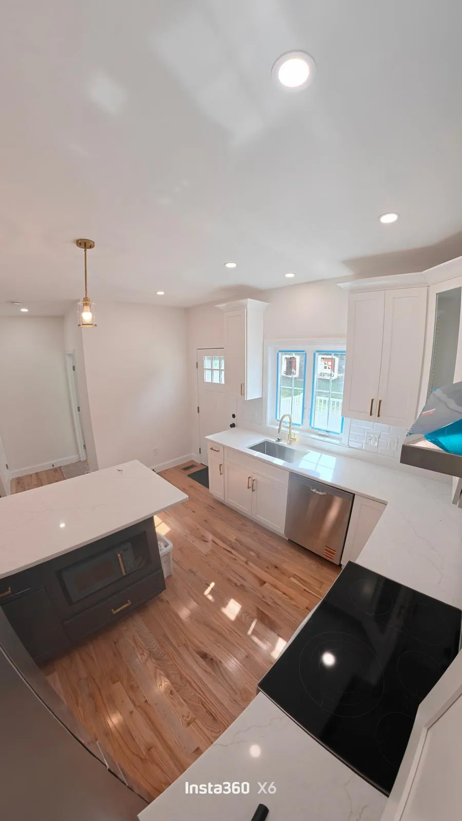 Completed custom kitchen with white cabinetry, quartz countertops, hardwood floors, and a contrasting island